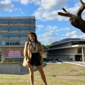 Student standing in a green field in front of one of University of Essex buildings